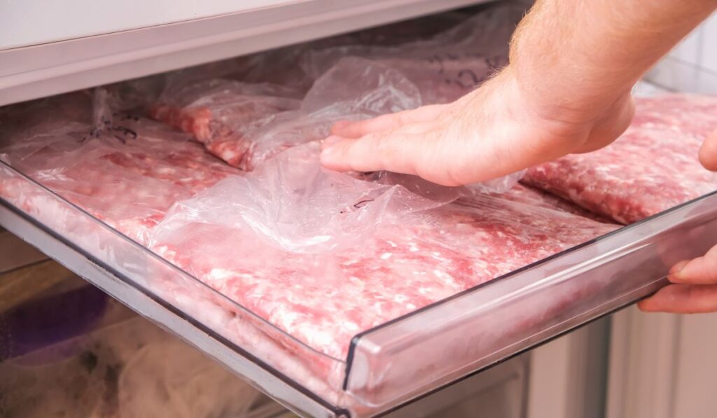 Man puts minced pork and beef in the freezer in serving bags for long storage